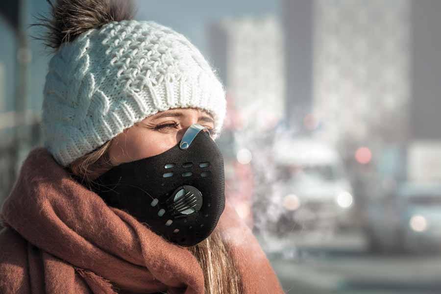 Dobre maski antysmogowe dokładnie przylegają do twarzy i zatrzymują ponad 99% szkodliwych substancji. Smog – kobieta w masce antysmogowej